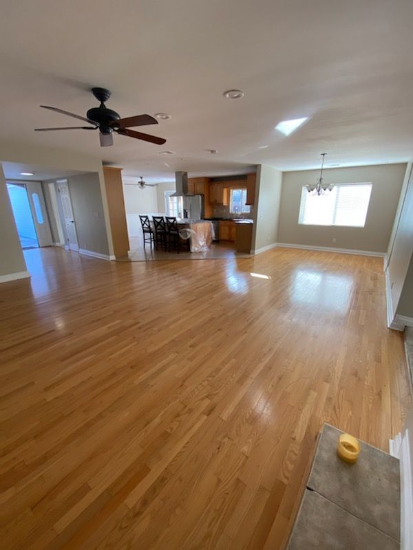 An empty living room with hardwood floors and a ceiling fan.