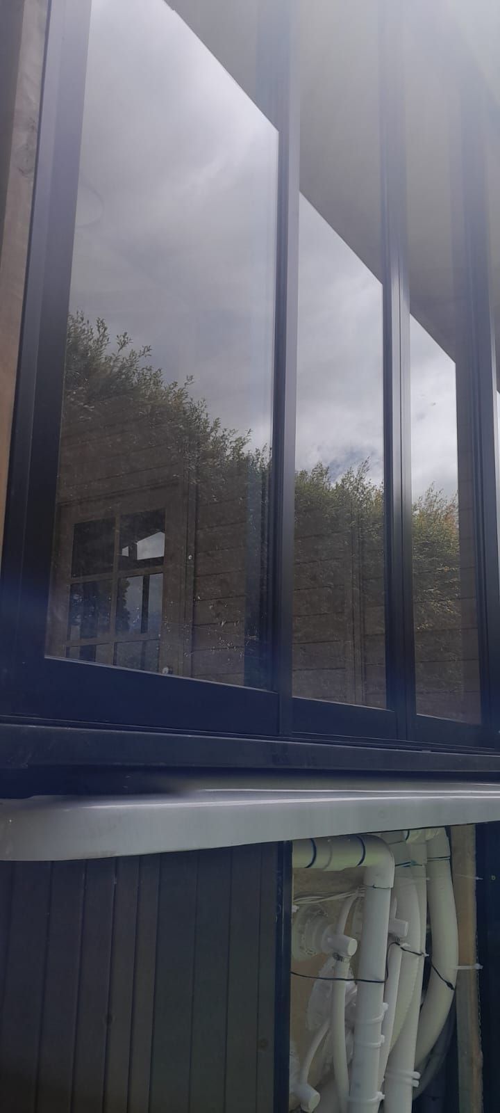 Paneles de ventanas azules reflectantes, revestimiento oscuro y tuberías blancas en la parte inferior