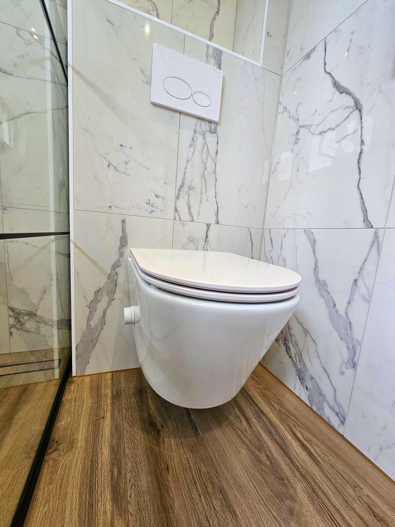Moderne badkamer met een hangtoilet, tegels met marmerlook en een vloer met houtlook.