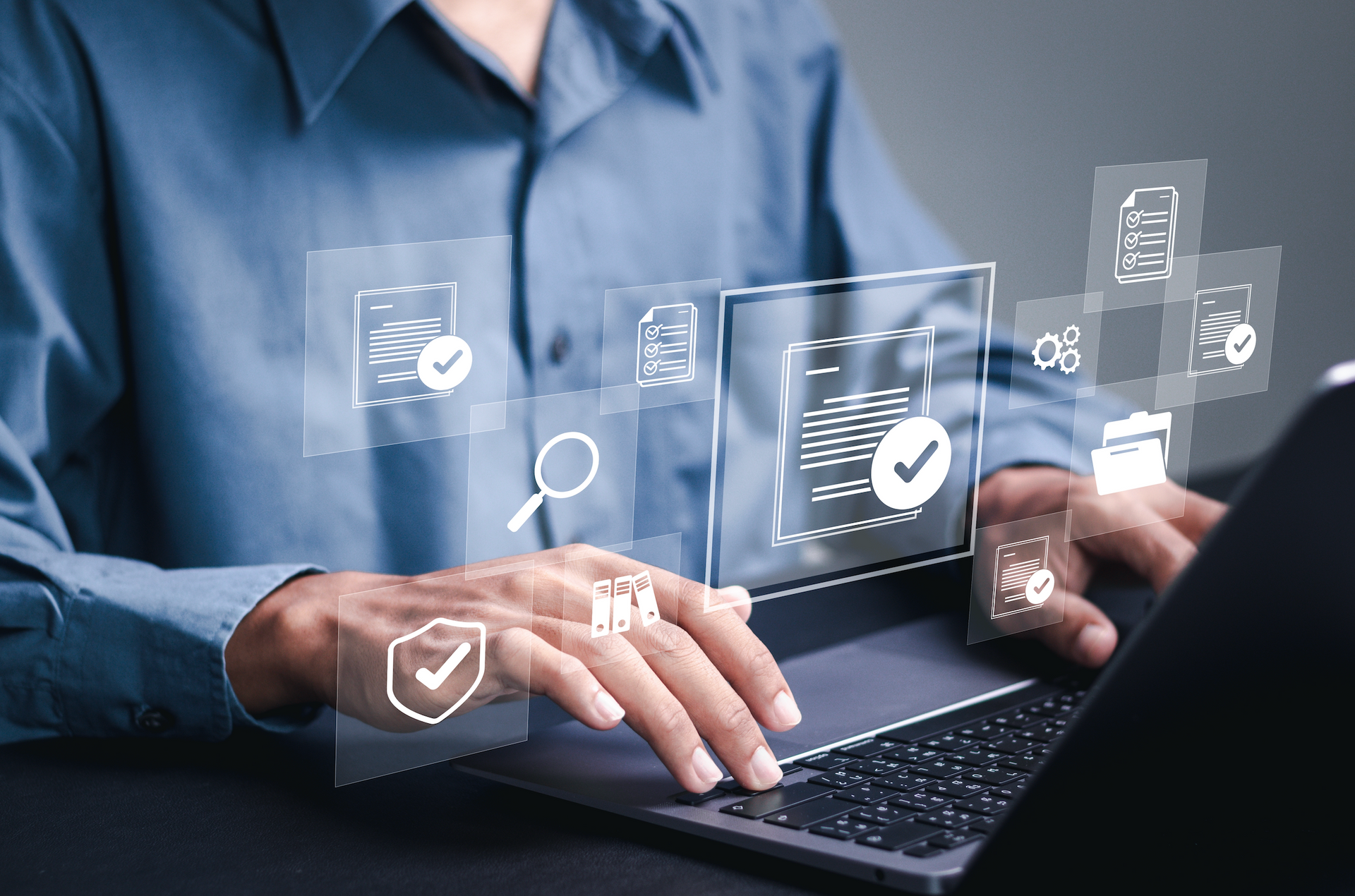A man is typing on a laptop computer with a virtual screen behind him.