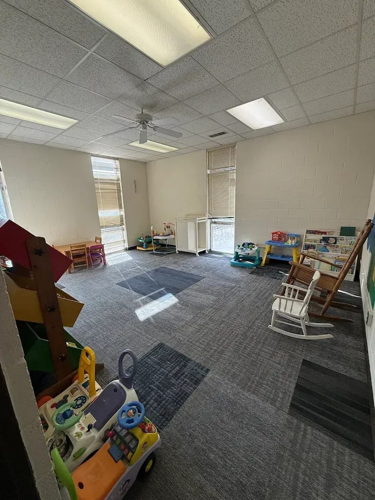 Bright classroom with carpet, shelves, toys, and sunlight on the floor