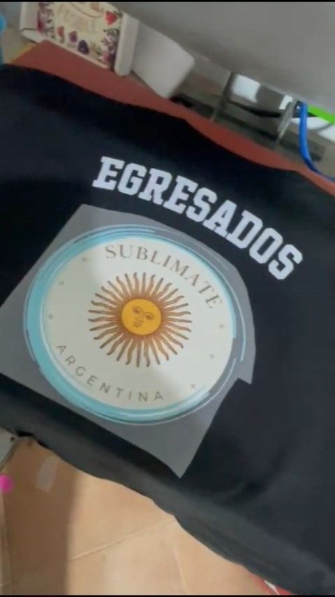 Camiseta negra con la inscripción “EGRESADOS” y el emblema de Argentina, doblada sobre una silla en el interior.