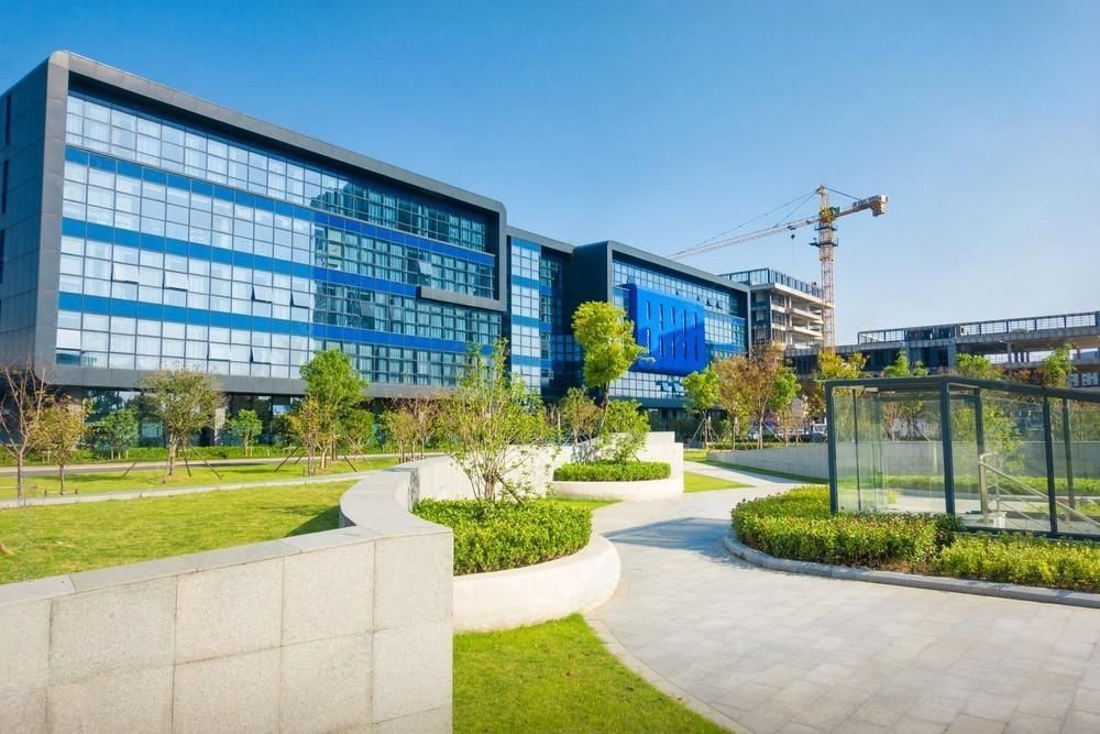 a large building with a lot of windows is surrounded by trees and grass .