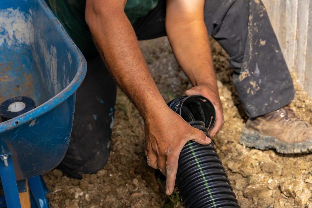 a man is using a vacuum hose to clean a drain .