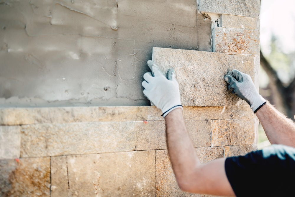 A skilled construction worker carefully placing bricks in a masonry wall using a trowel.
