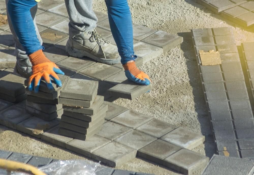 a person is laying bricks on a sidewalk .