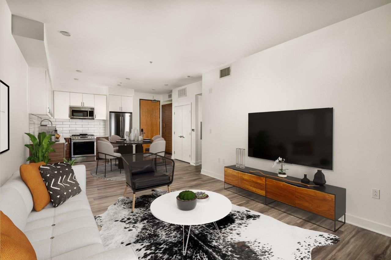 An open-concept apartment layout showcasing a white sectional sofa, cowhide rug, television console