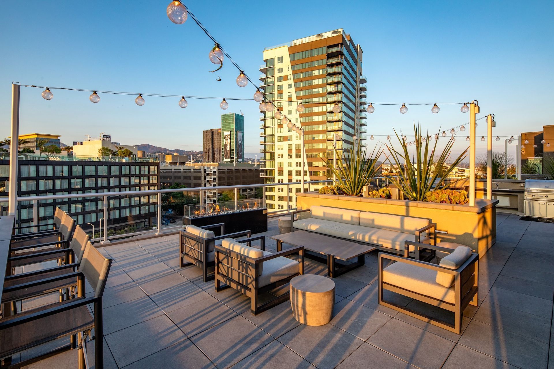 A modern rooftop lounge at The Ovelo Hollywood featuring glass railings and greenery under a clear blue sky.