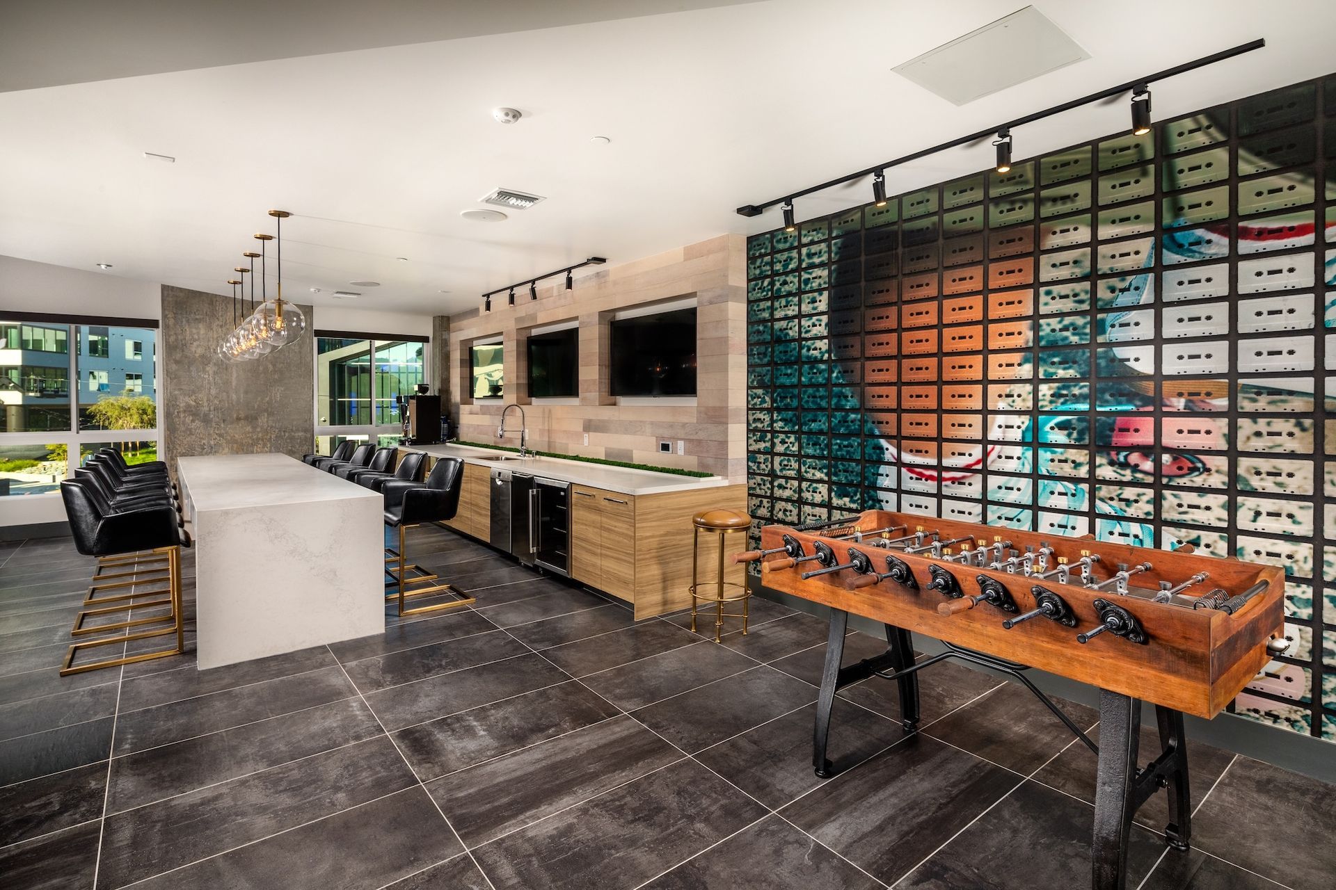 Game room with foosball table, bar, TVs, and colorful wall art.