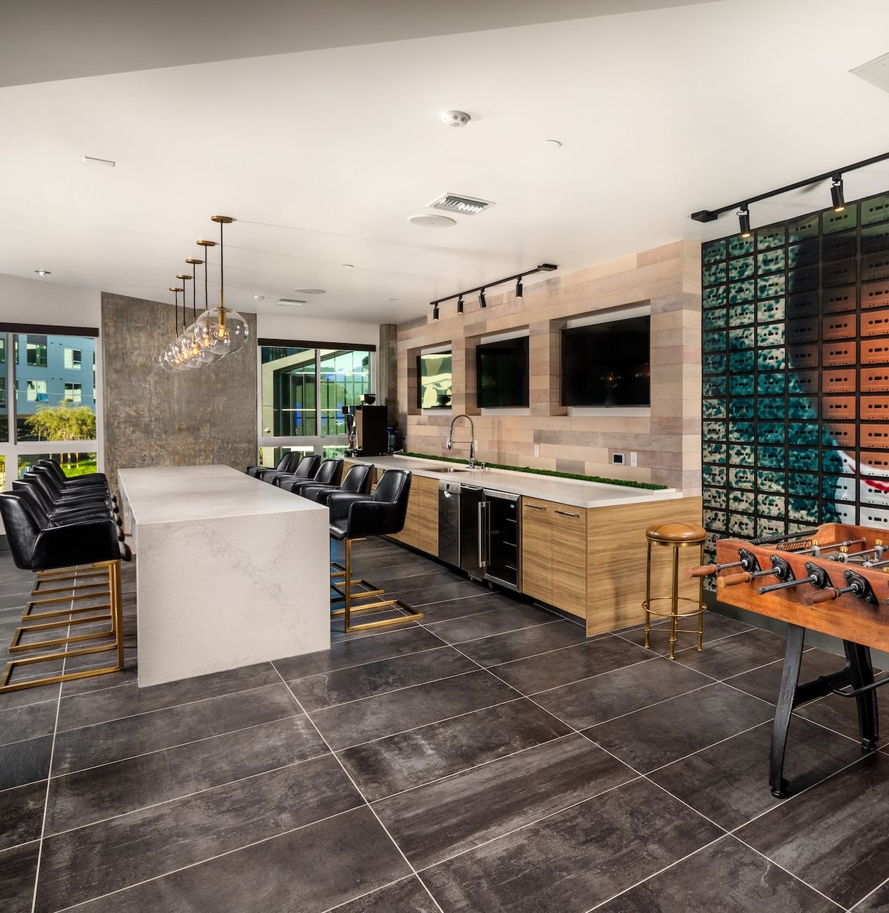 Lounge area with modern decor: gold ring lights, patterned wall, wood and metal furniture.
