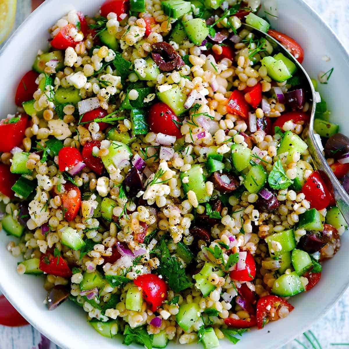 Mediterranean couscous bowl with chickpeas, cucumber, tomatoes, and feta cheese in a light, fresh presentation.