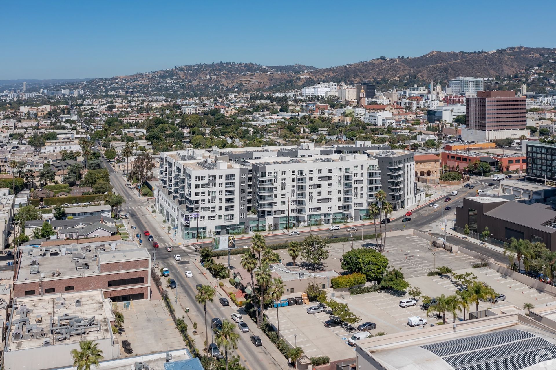 The white luxury Ovelo Hollywood apartment building standing on a city street corner near cars