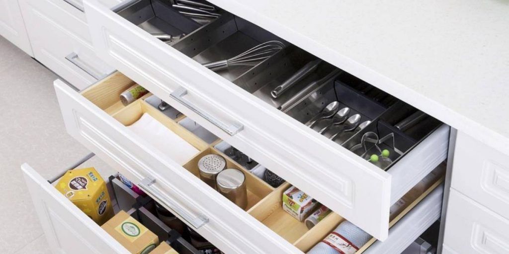 White cabinet drawers with space saving storage items for kitchen tools, spices, silverware with dividers and sectioned out areas.