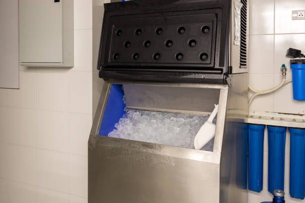 An ice machine with lid open, revealing a bin of ice. A scoop rests inside.