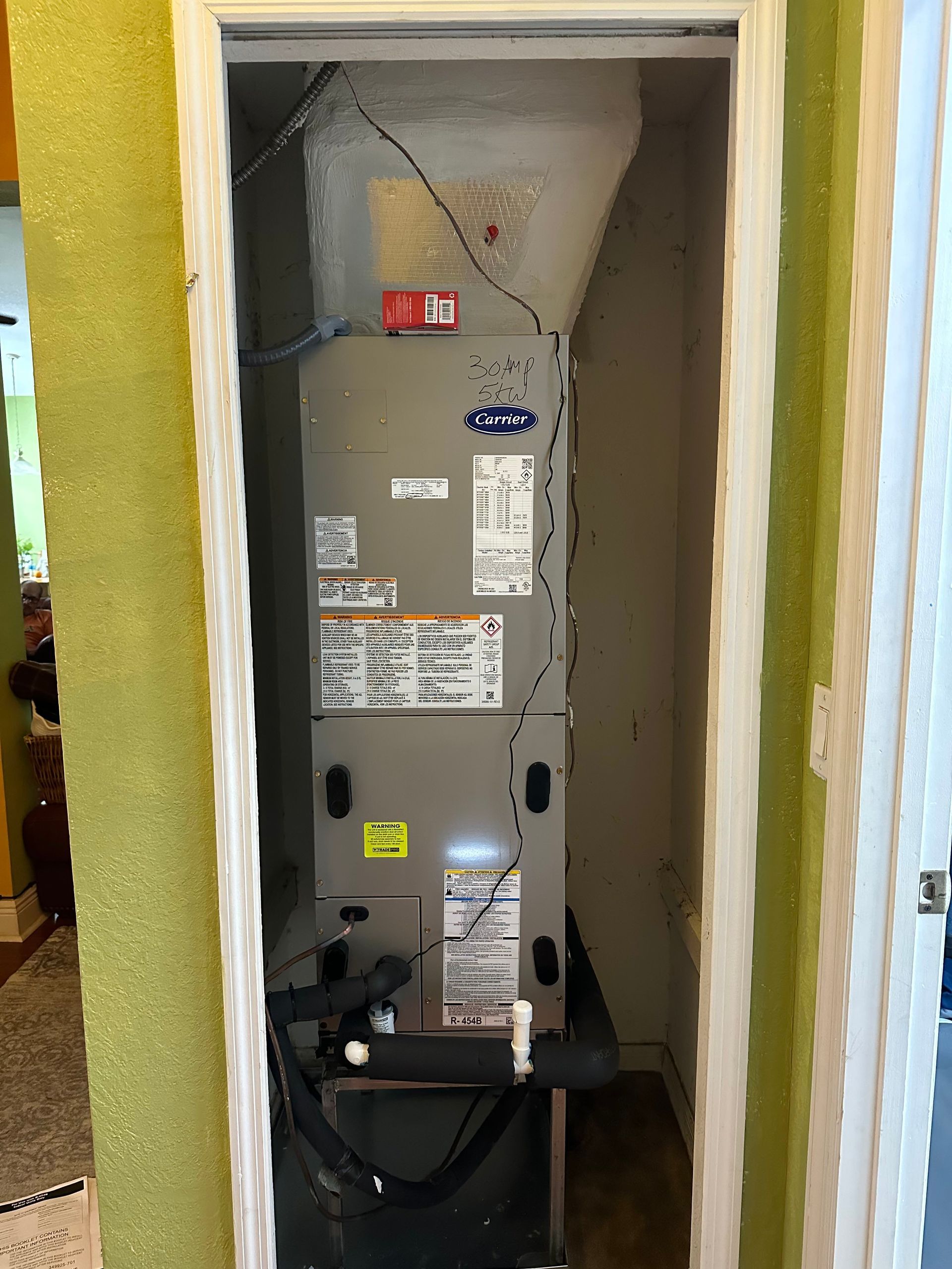Open HVAC furnace in a wall closet with exposed wires and venting.