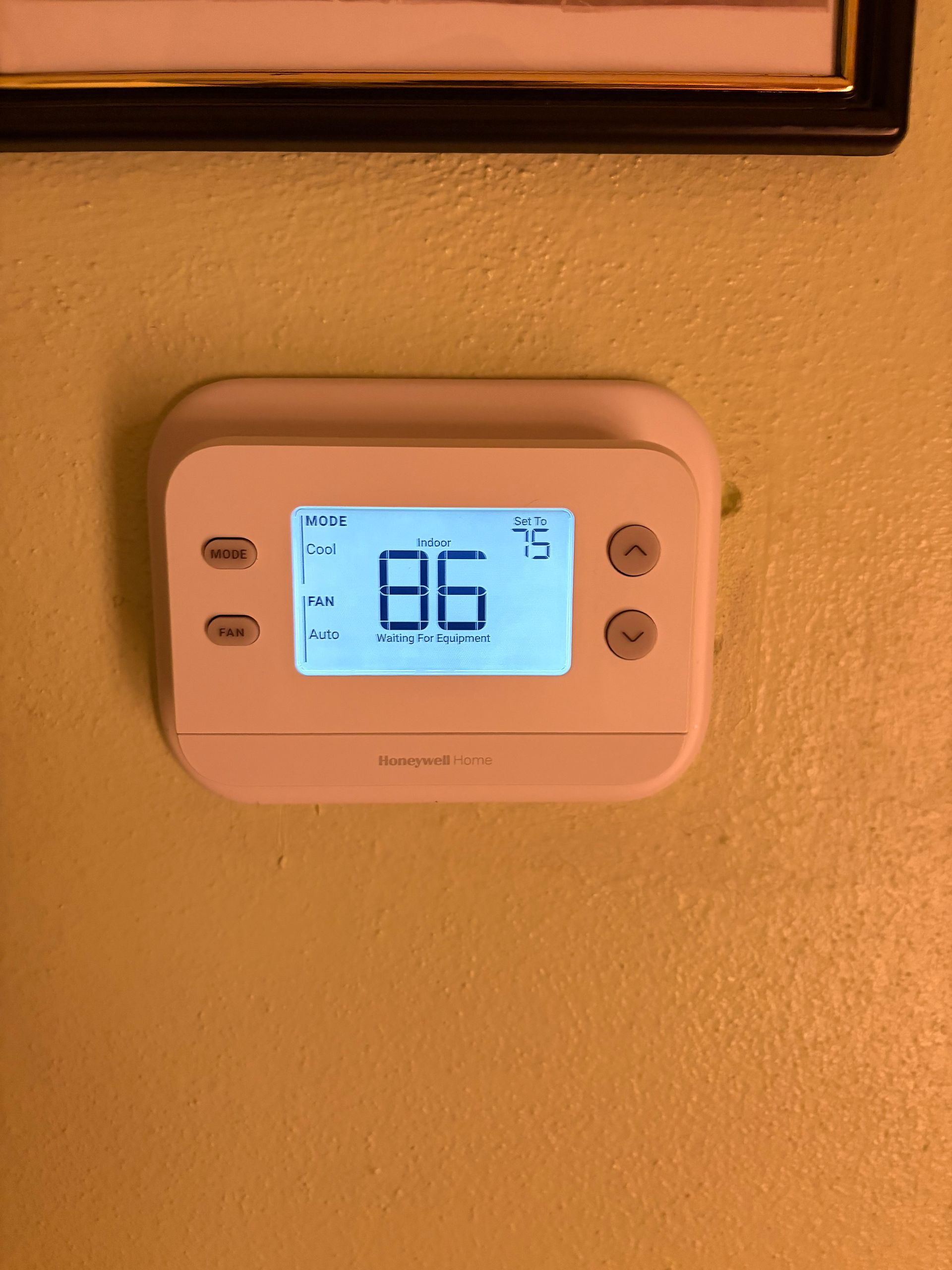 Wall thermostat with blue digital display on an orange wall