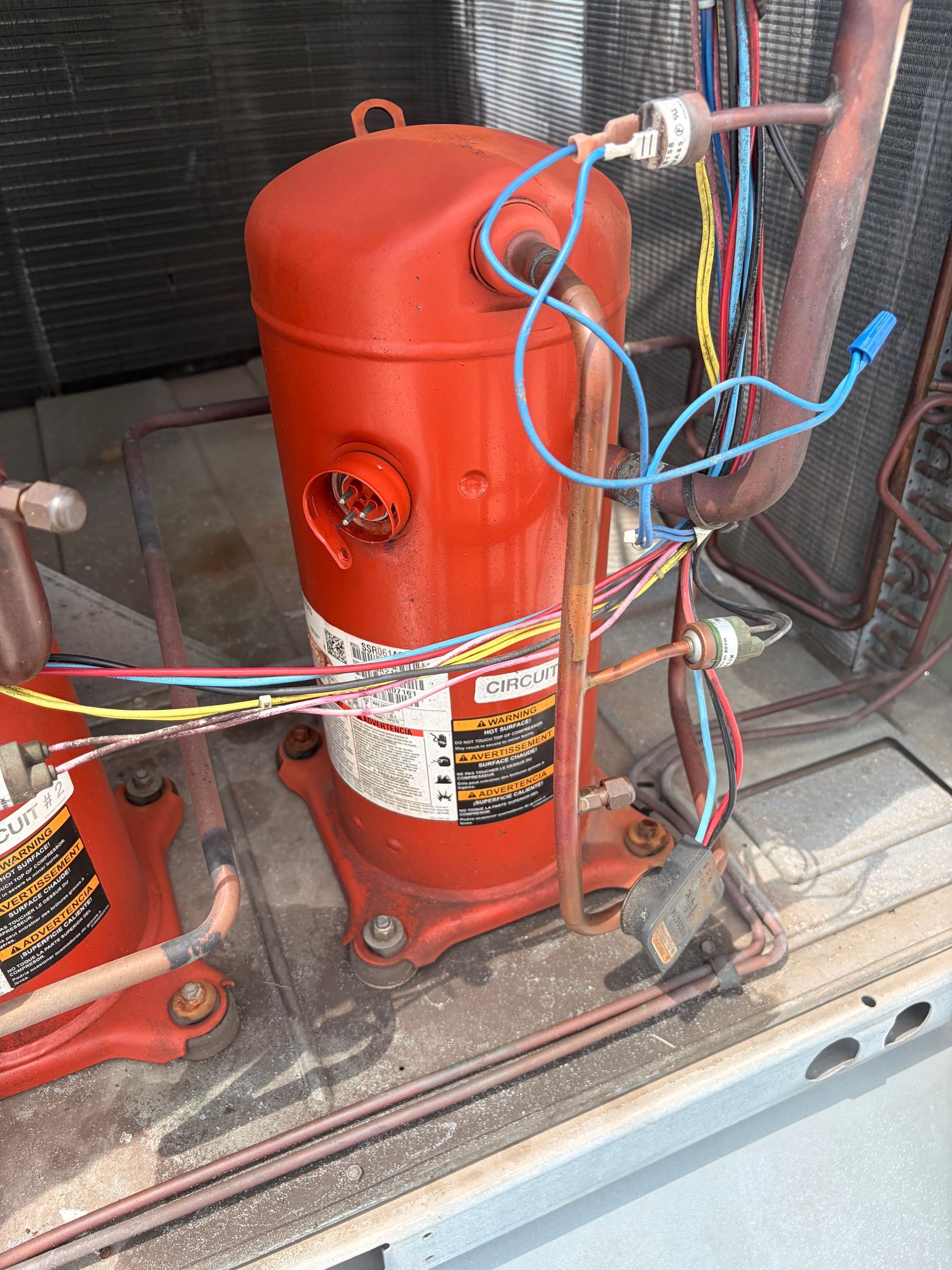 Red industrial compressor or tank with exposed wires and hoses inside a metal cabinet.