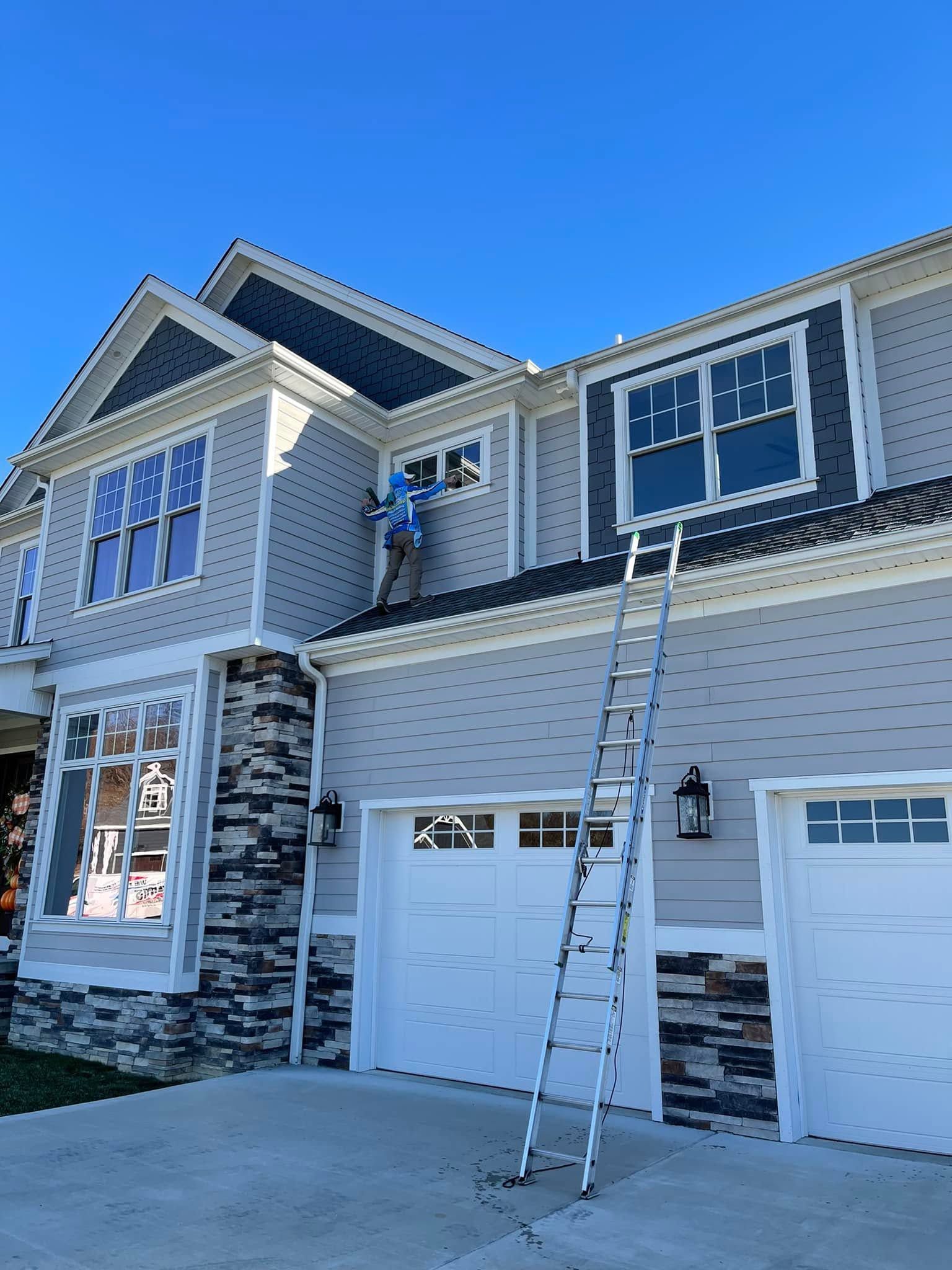Two-story house exterior with white siding, stone accents, and a ladder leaning against the second floor