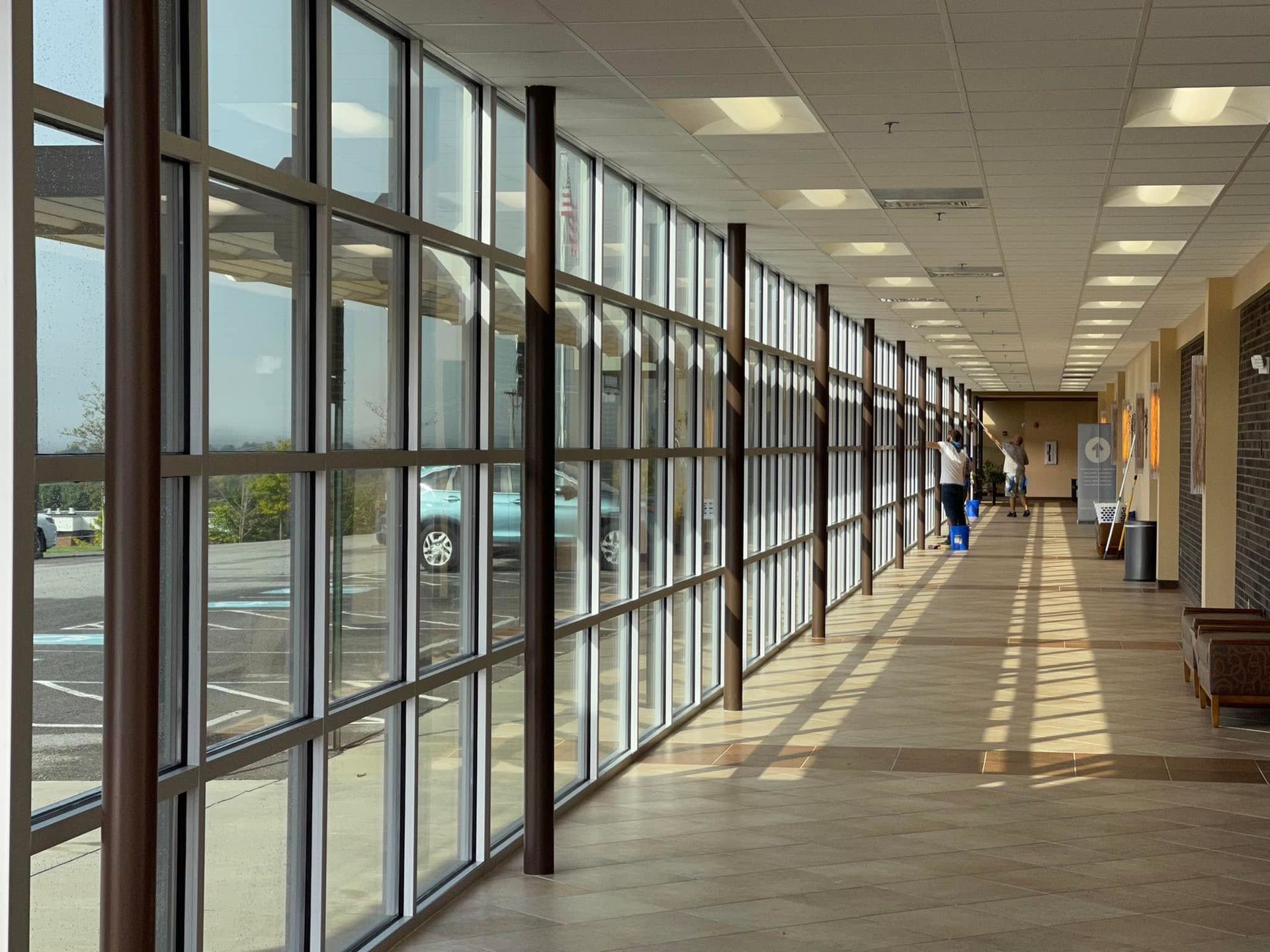 Sunlit empty shopping mall corridor with glass storefronts and long shadows