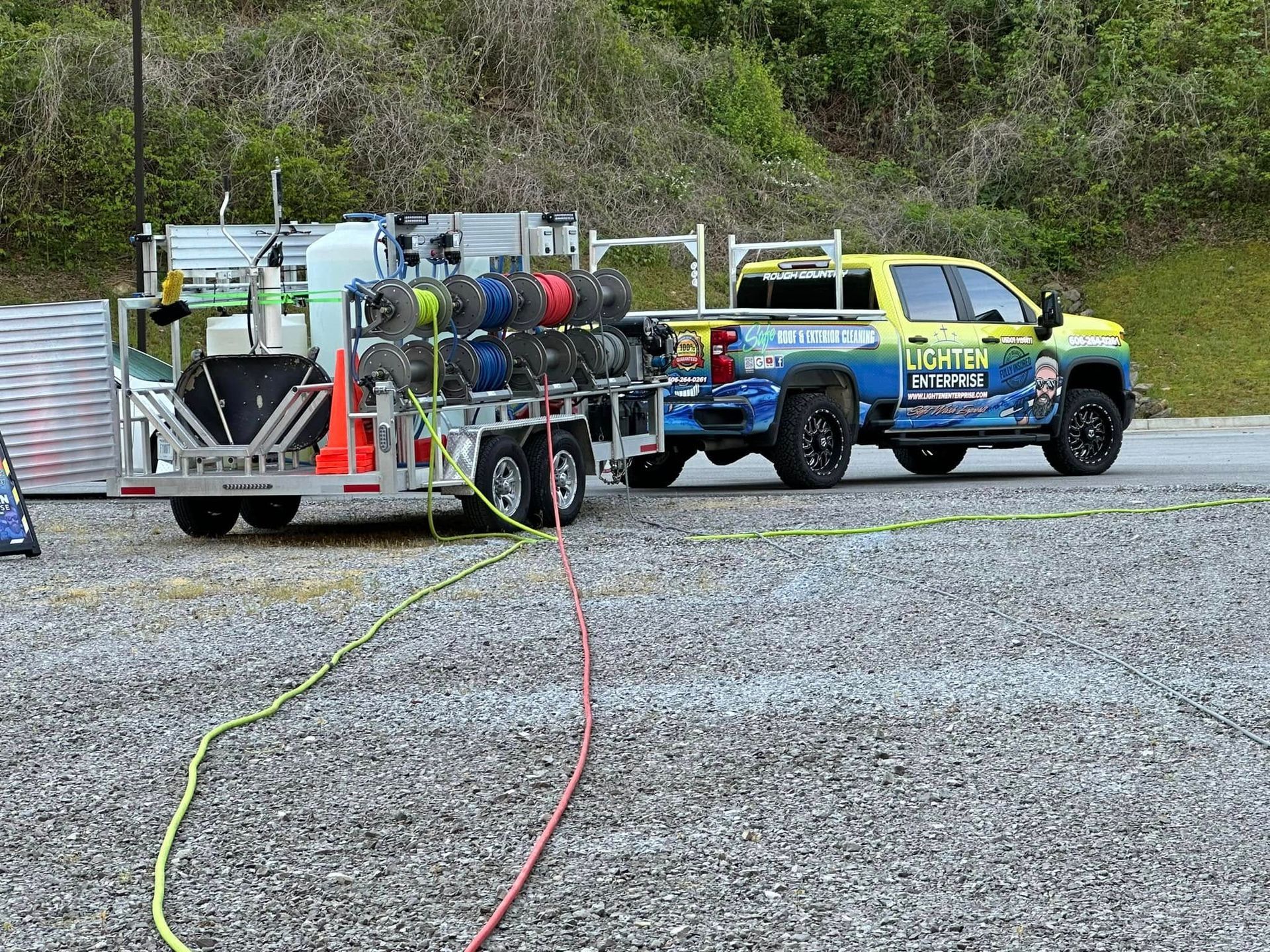 Yellow-blue pickup truck towing fire equipment on a gravel lot with hoses stretched out.