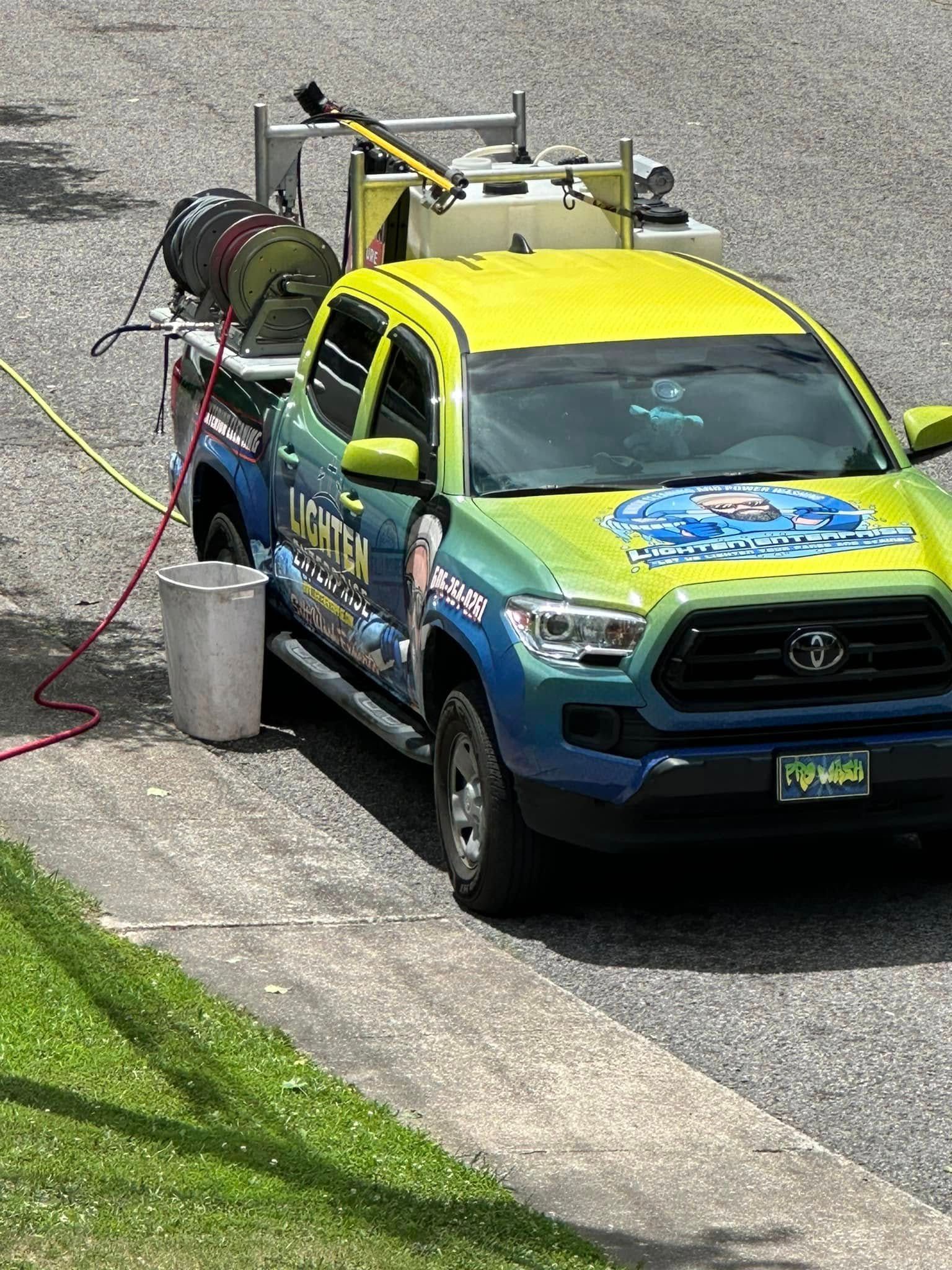 Utility truck spraying liquid on a street beside a grassy slope