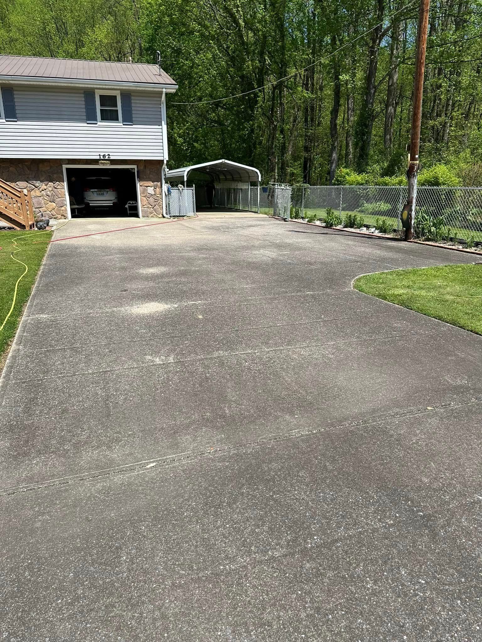 Driveway leading to a stone garage beside a fenced yard and trees.