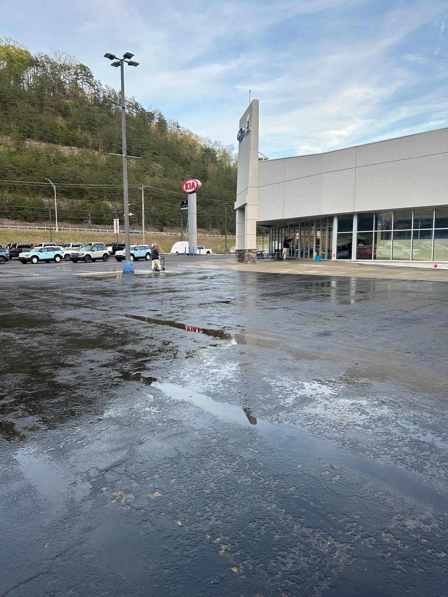 Flooded parking lot beside a modern building under a cloudy sky
