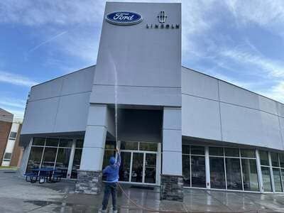 Person standing outside a Ford dealership with large glass windows and a curved gray facade.