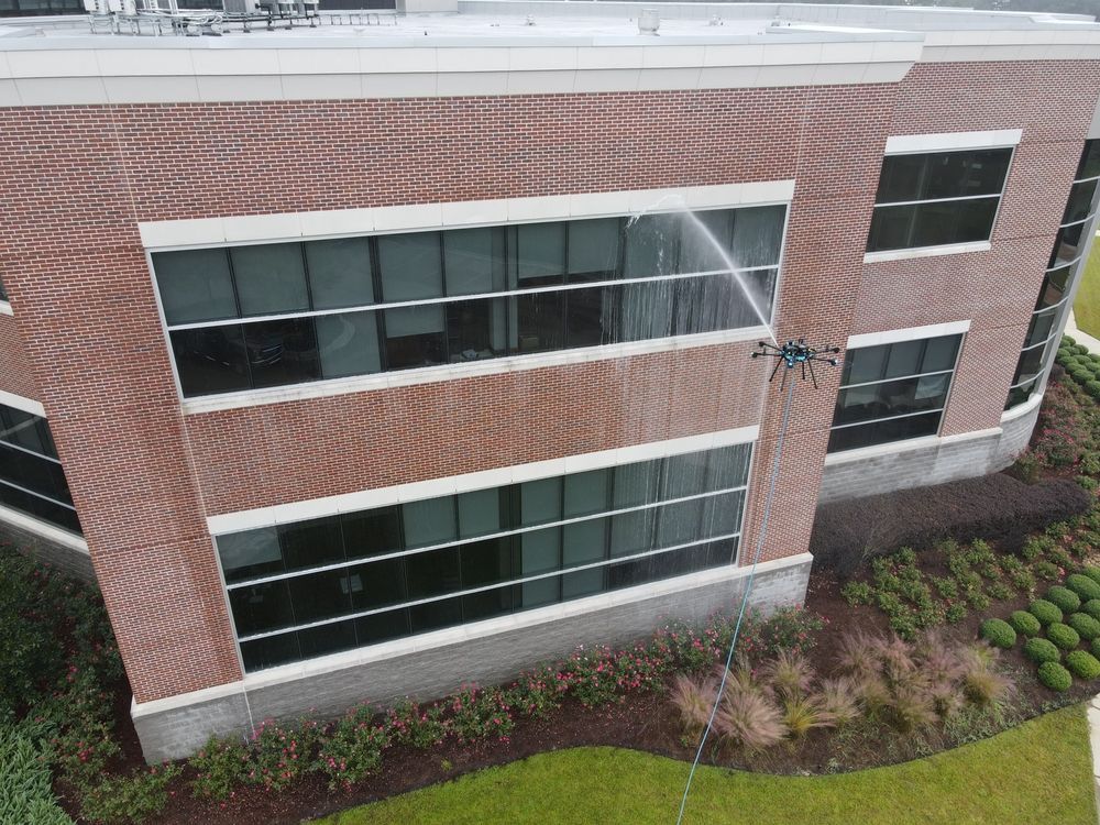 Brick office building with long dark windows and landscaped shrubs along the base