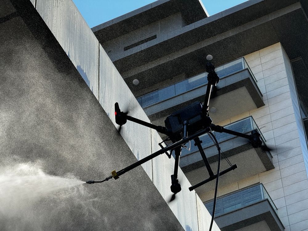 Drone spraying water at the side of a tall building