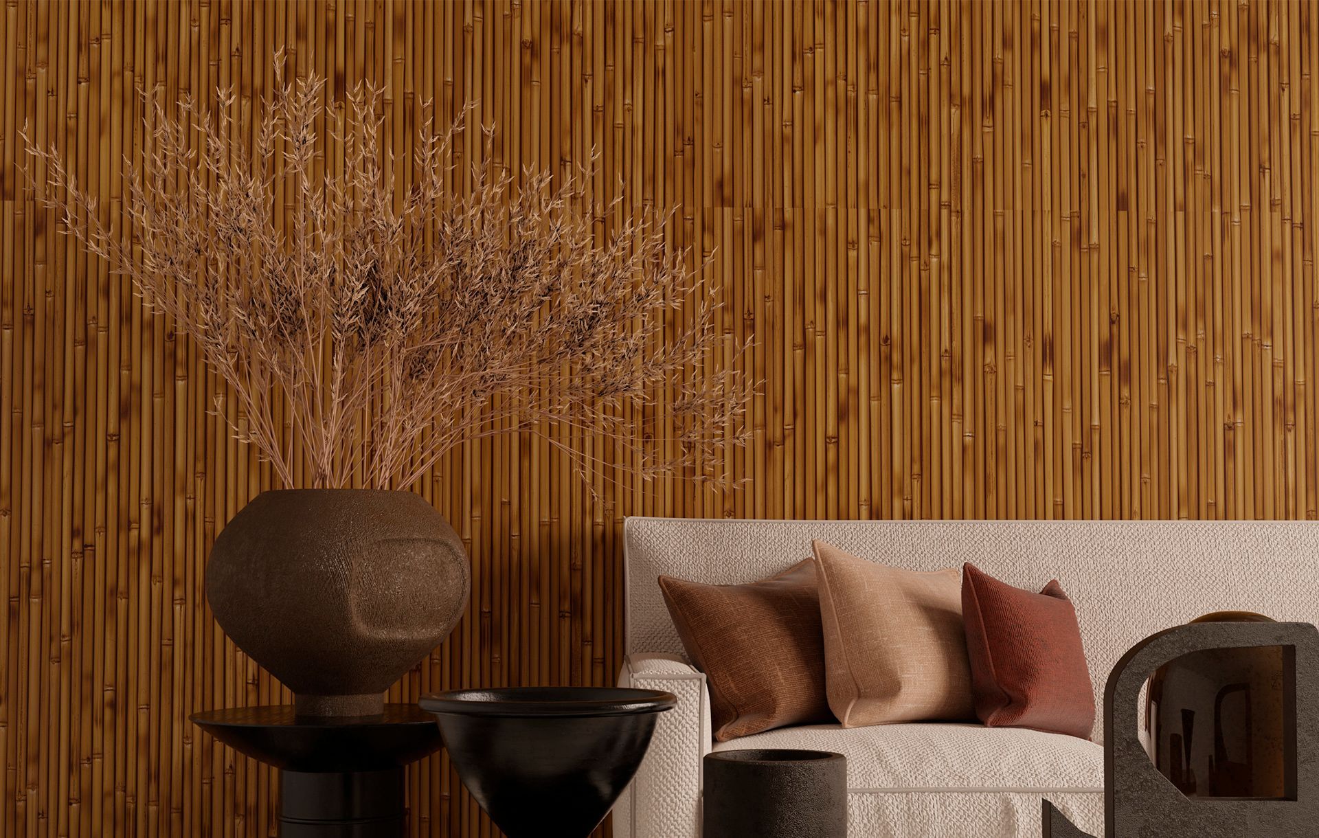 Um sofá bege com três almofadas está encostado em uma parede escura de bambu com ripas verticais, com um vaso de galhos em primeiro plano.