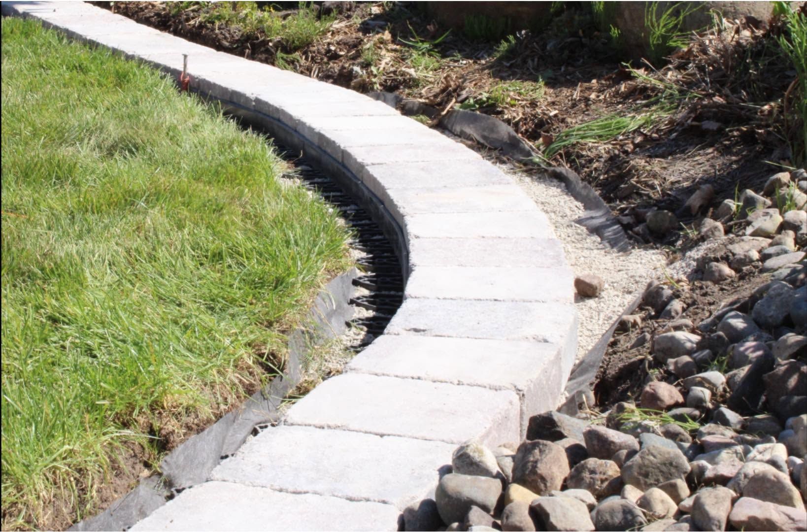 Curved concrete walkway beside green grass and rocky landscaping