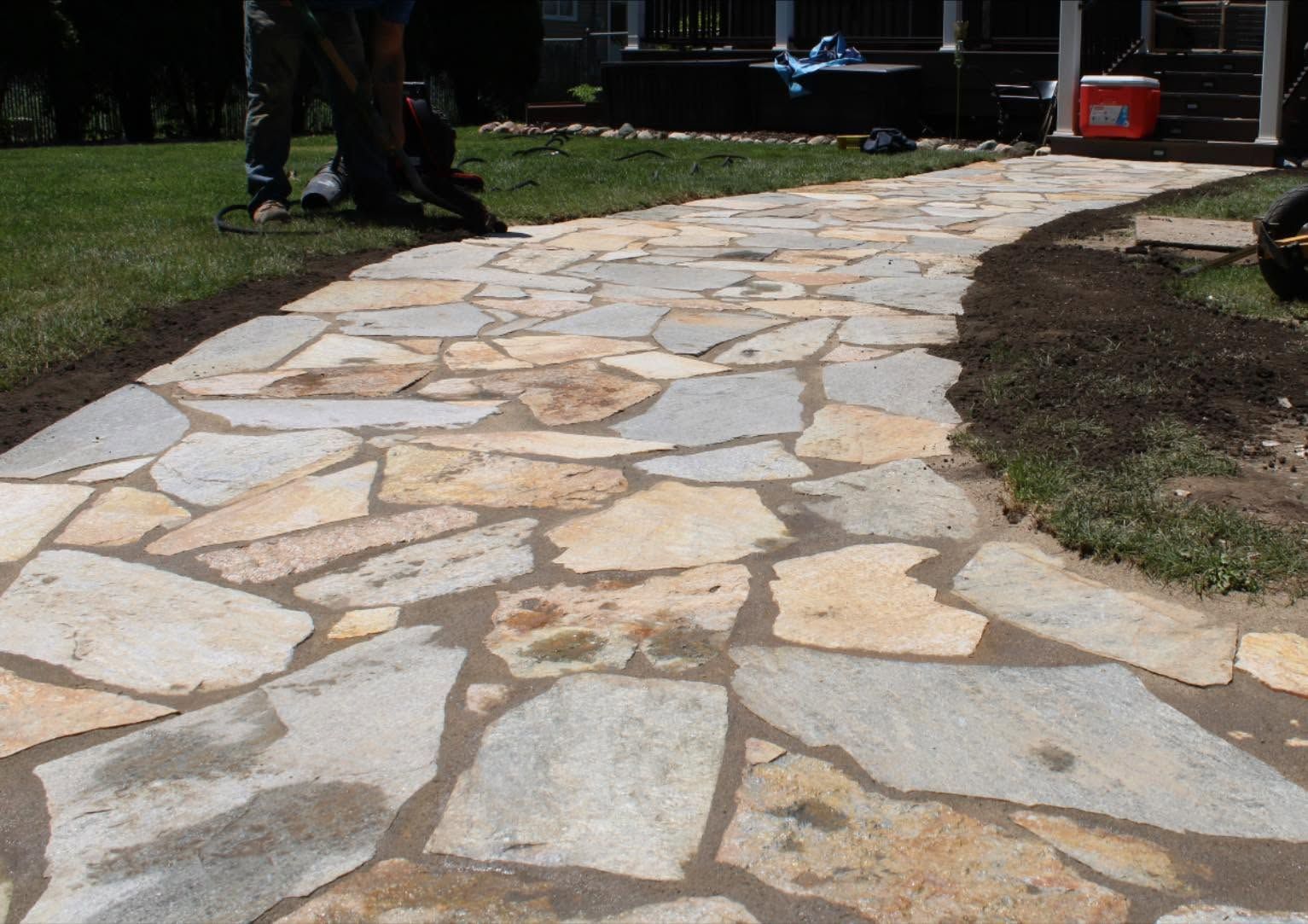 Stone walkway curving through grass with a few people standing in the background