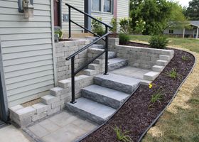 Irregular tan and gray stone pavers set in dark soil, forming a decorative path outdoors