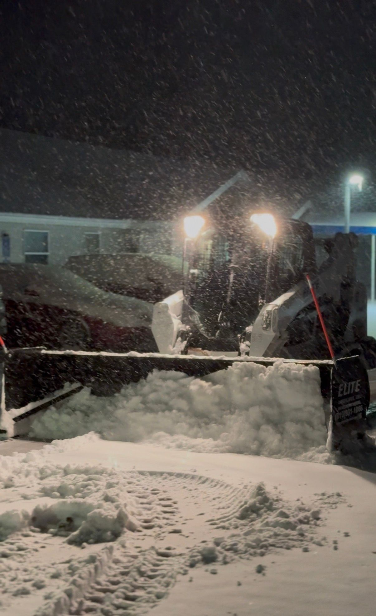 Tow truck with bright headlights and red equipment parked in a garage at night