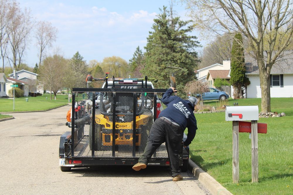 Worker unloading equipment from a trailer on a suburban street beside a mailbox