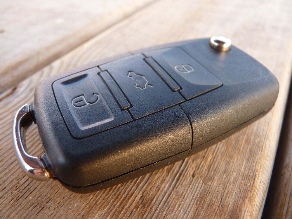 Black Car Key Fob with Three Buttons on A Wooden Surface — Terrace Locksmiths in Raymond Terrace, NSW