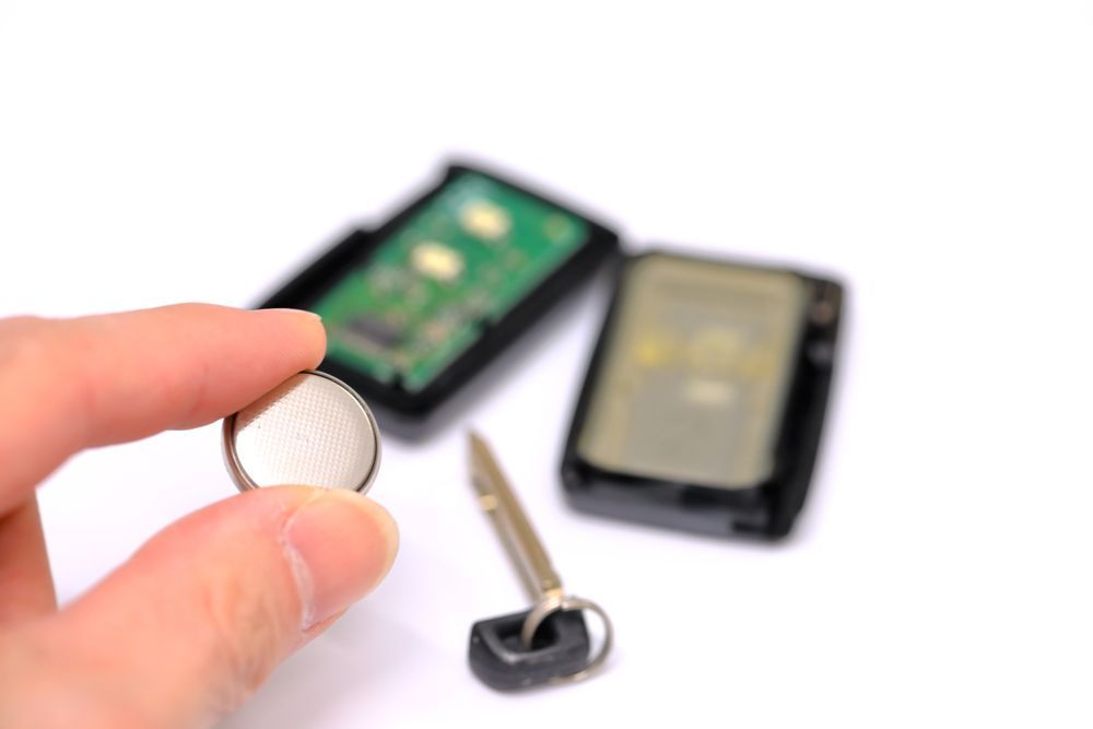 Coin Cell Battery Held Near Two Disassembled Key Fobs — Terrace Locksmiths in Raymond Terrace, NSW