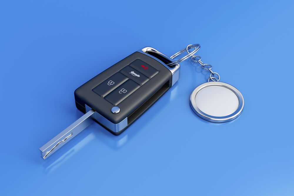Car Key Fob with A Metal Key Blade and Round Keyring on A Blue Background — Terrace Locksmiths in Raymond Terrace, NSW