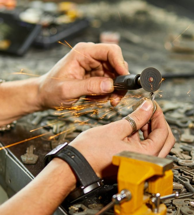 Hands using a rotary tool to cut metal, with sparks flying on a workbench. — Terrace Locksmiths in Raymond Terrace, NSW