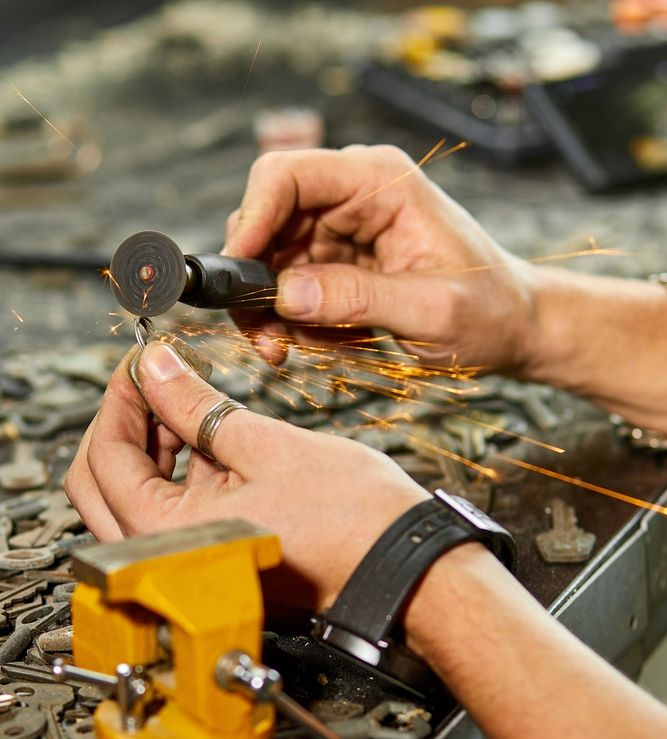 Hands Using a Small Tool on A Metal Workbench, with A Yellow Vise in The Foreground — Terrace Locksmiths in Cessnock, NSW