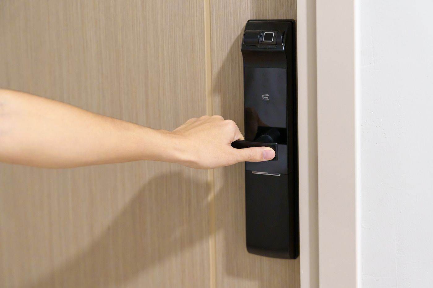 Hand Pressing a Black Door Access Button on a Wooden Door — Terrace Locksmiths in Raymond Terrace, NSW