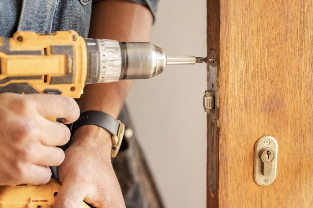 Person Using a Drill to Remove a Door Lock from A Wooden Door — Terrace Locksmiths in Charlestown, NSW