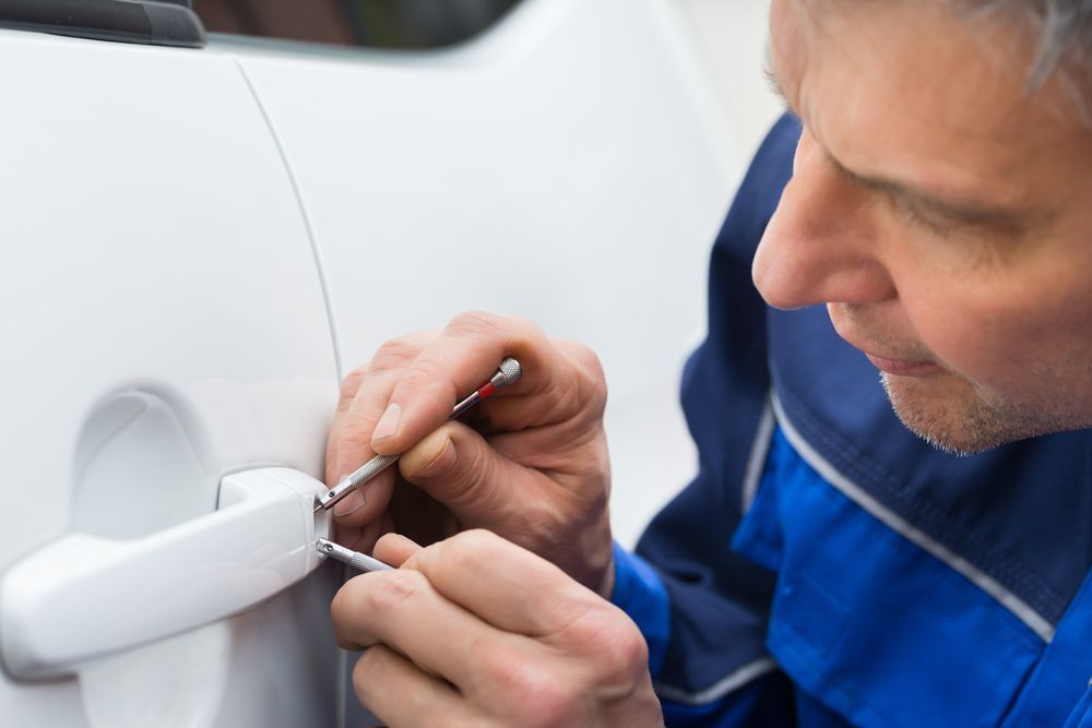 Man Using a Tool to Unlock a White Car Door — Terrace Locksmiths in Maitland, NSW