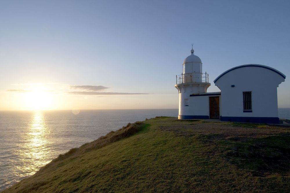 Sunset Over the Ocean Beside a White Lighthouse on A Grassy Cliff — Terrace Locksmiths in Port Stephen, NSW
