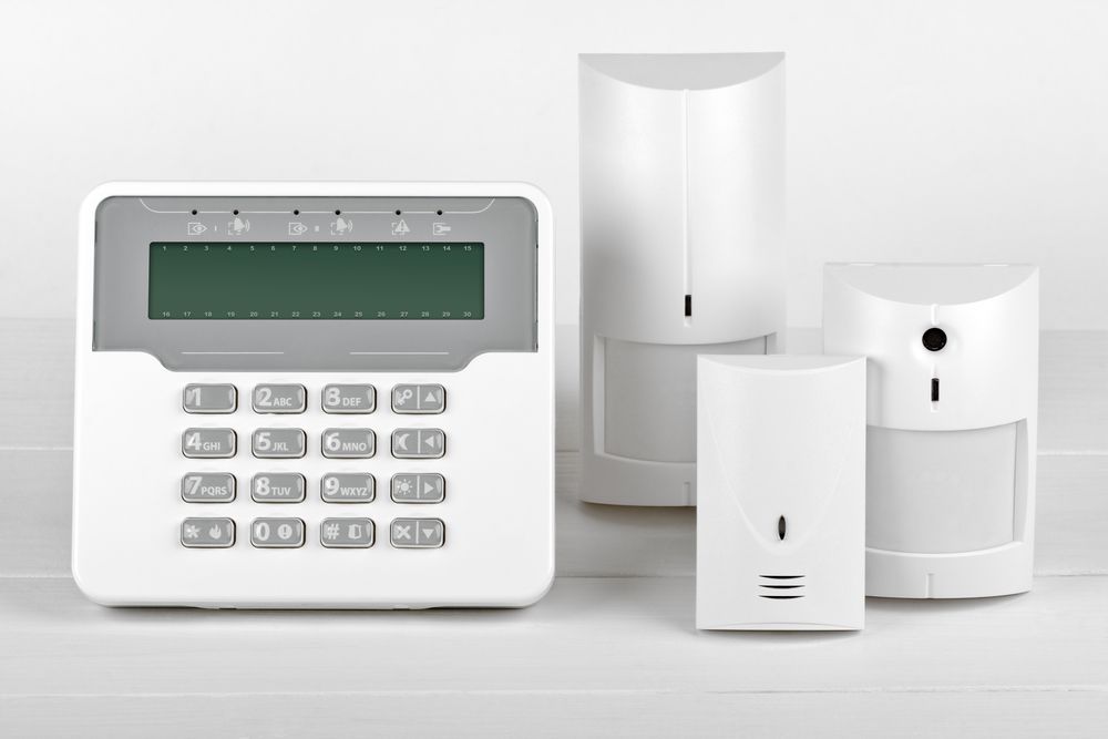 Home security alarm keypad with three white motion sensors on a light background — Terrace Locksmiths in Raymond Terrace, NSW