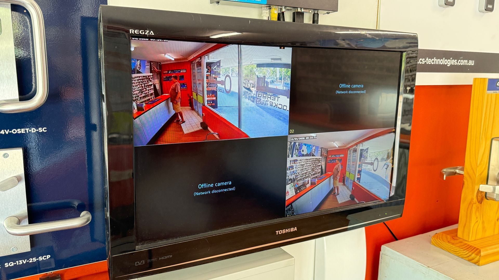 Security monitor showing four CCTV camera views inside a train or transit car, with red interior accents— Terrace Locksmiths in Raymond Terrace, NSW