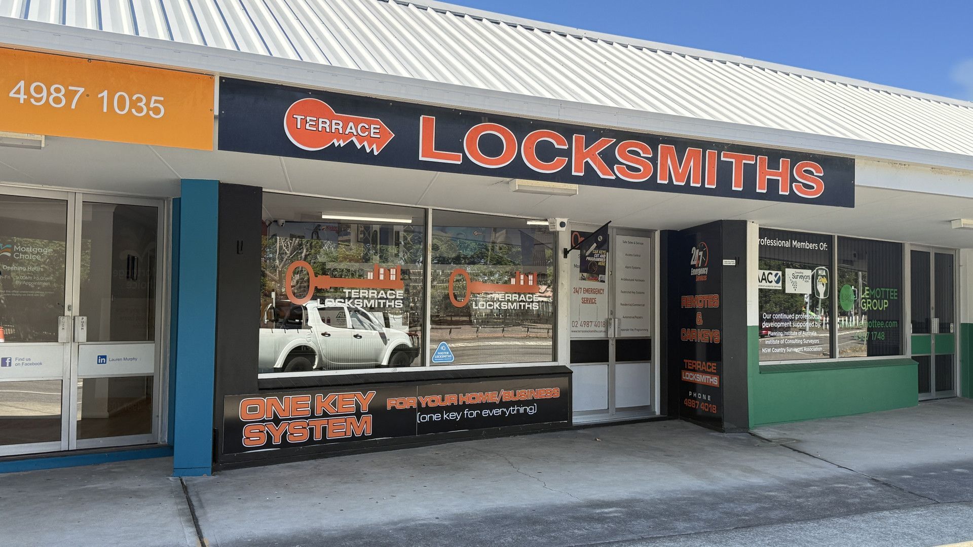 Locksmith Storefront with Orange and Black Signage on A Sunny Street — Terrace Locksmiths in Cessnock, NSW