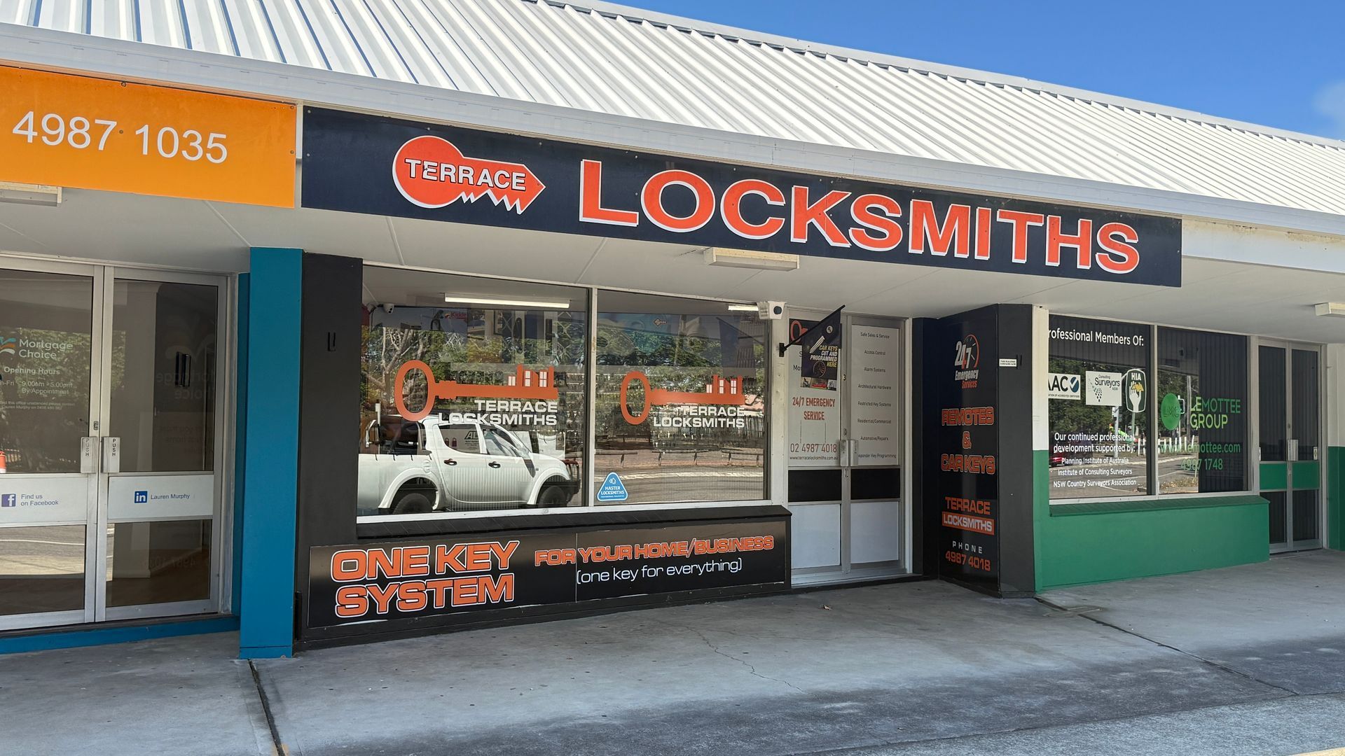 Storefront of a locksmith business with orange and black signage and glass windows. — Terrace Locksmiths in Raymond Terrace, NSW
