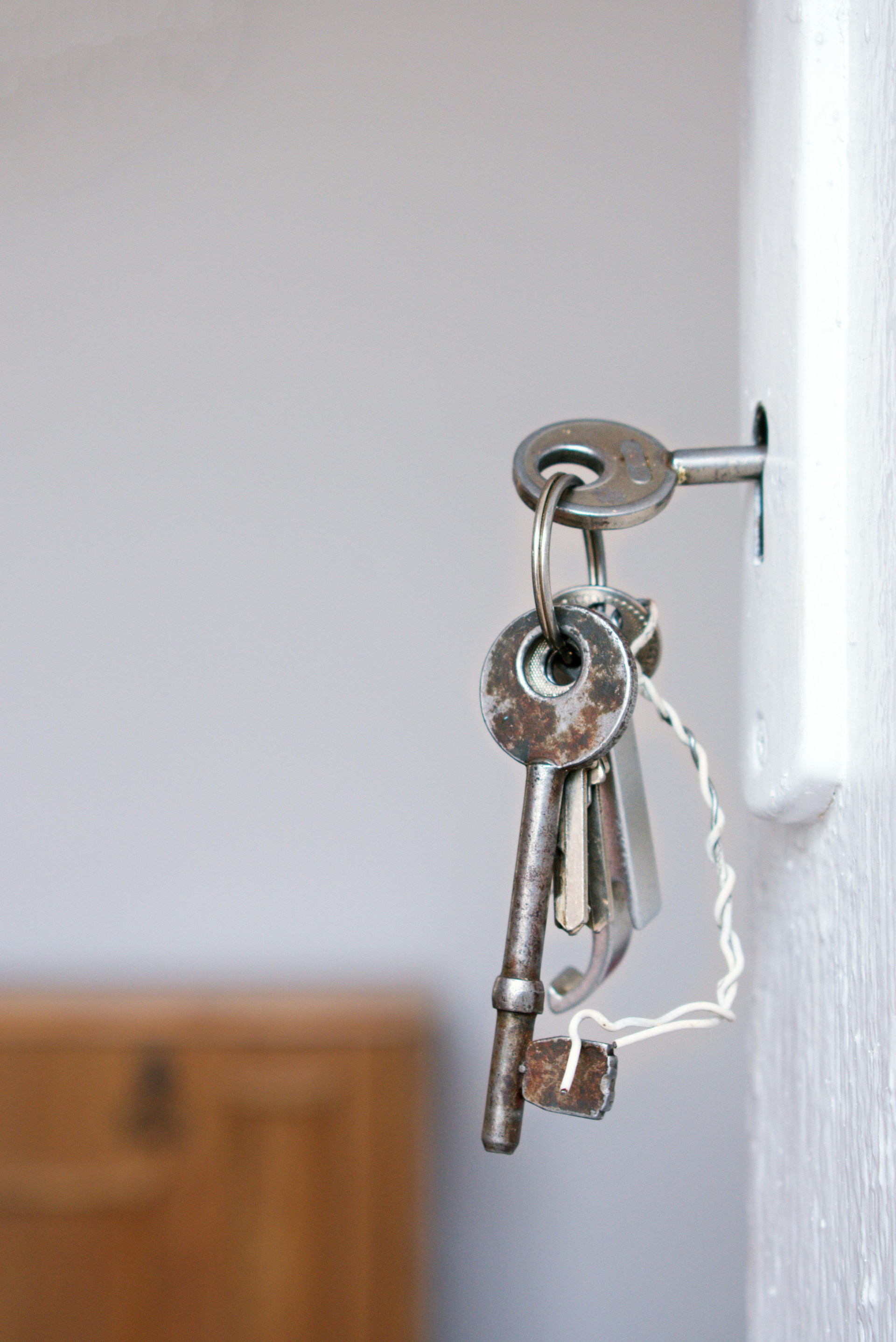 Keys Hanging in A Door Lock on A White Wall — Terrace Locksmiths in Maitland, NSW